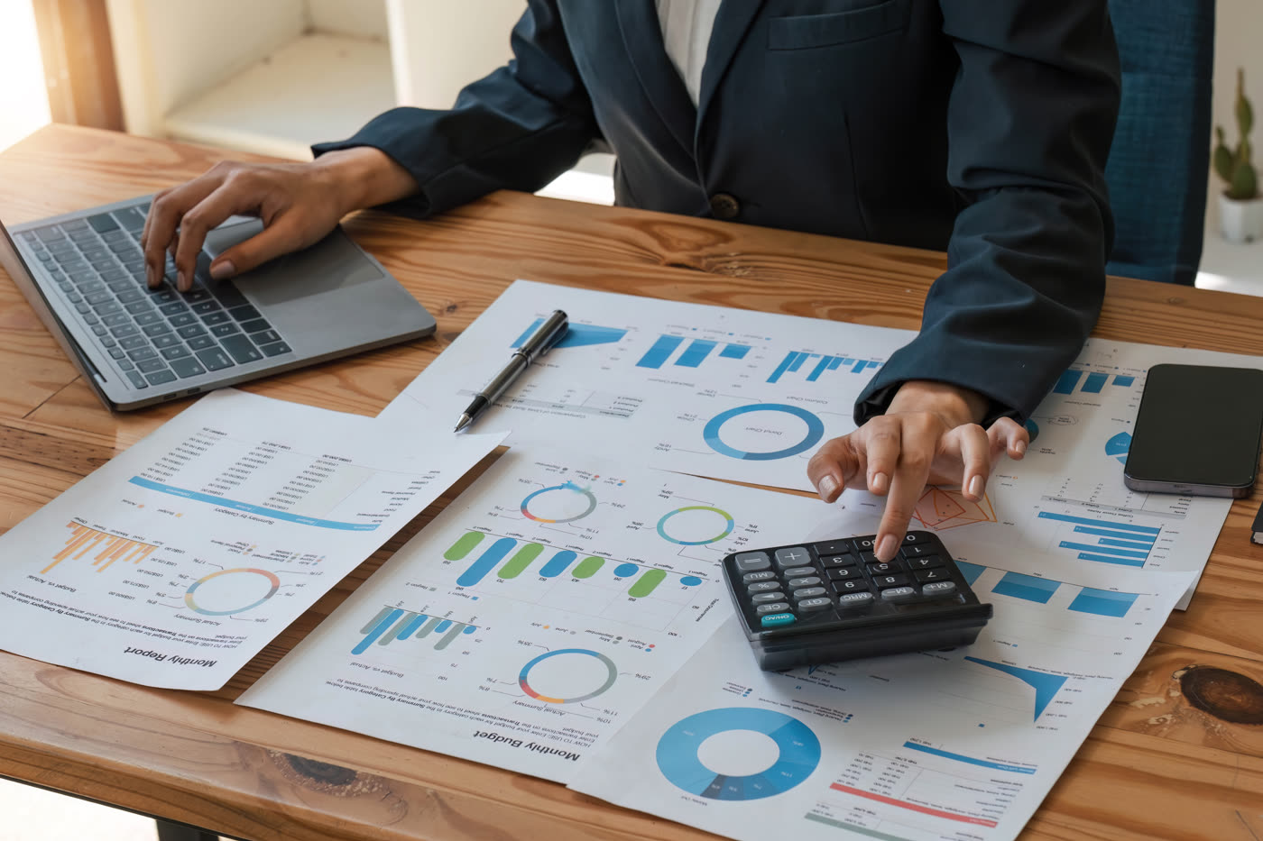 An accountant working through printed charts at a desk with a calculator